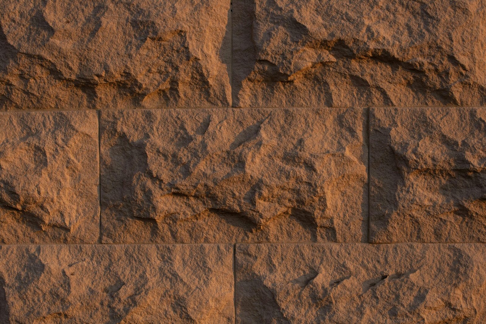 Close-up of a rough textured stone wall with natural patterns and earthy tones.